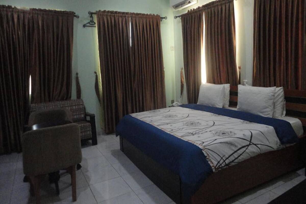 A bedroom with a bed, a chair, and curtains.