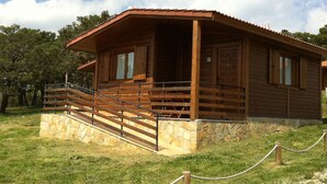 Una cabaña de madera con cimientos de piedra, un porche de madera y una escalera que lleva a la entrada.