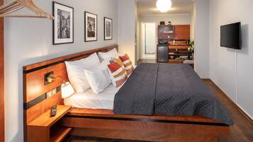 Un dormitorio moderno con una cama de madera, una mesita de noche y un televisor montado en la pared.