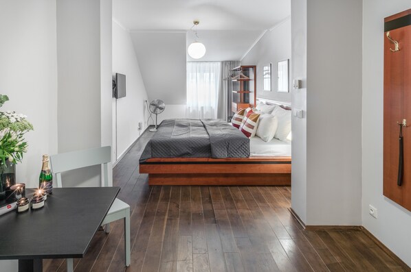 A modern bedroom with a loft bed, a small table with candles, and a fan.