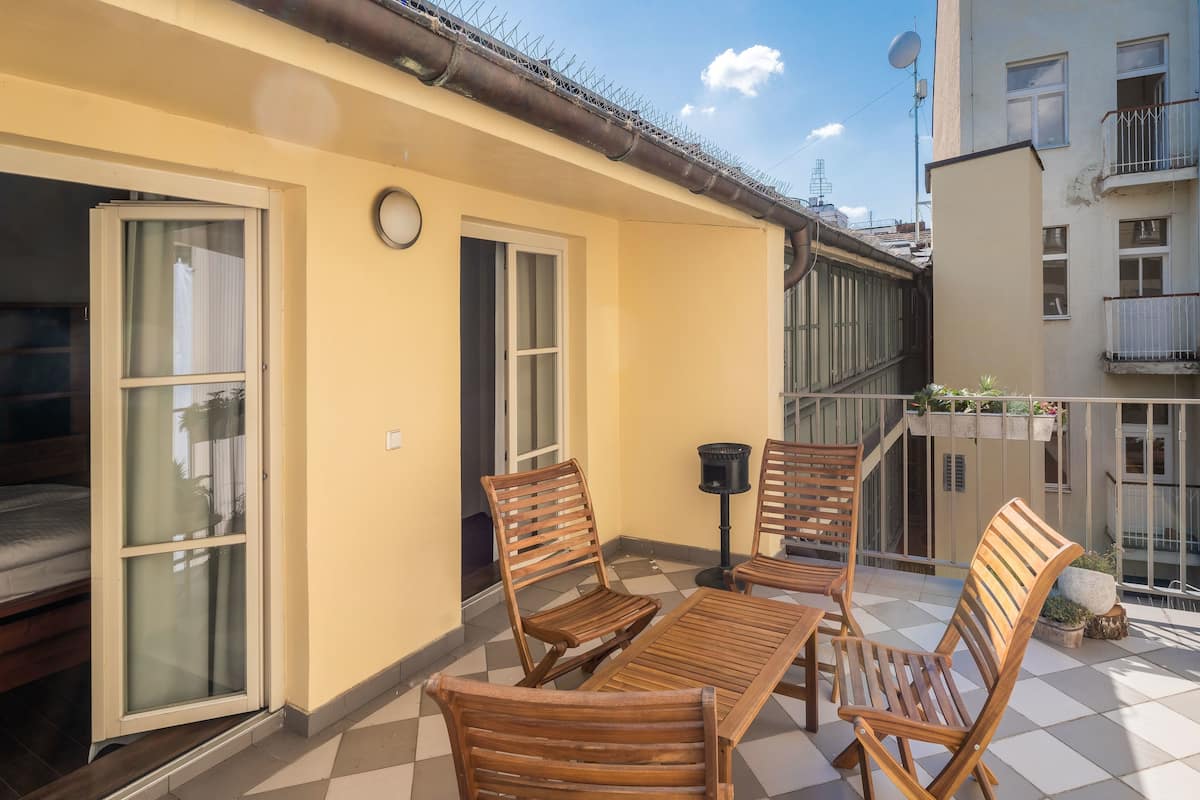 A balcony with wooden furniture, a small table, and a potted plant.