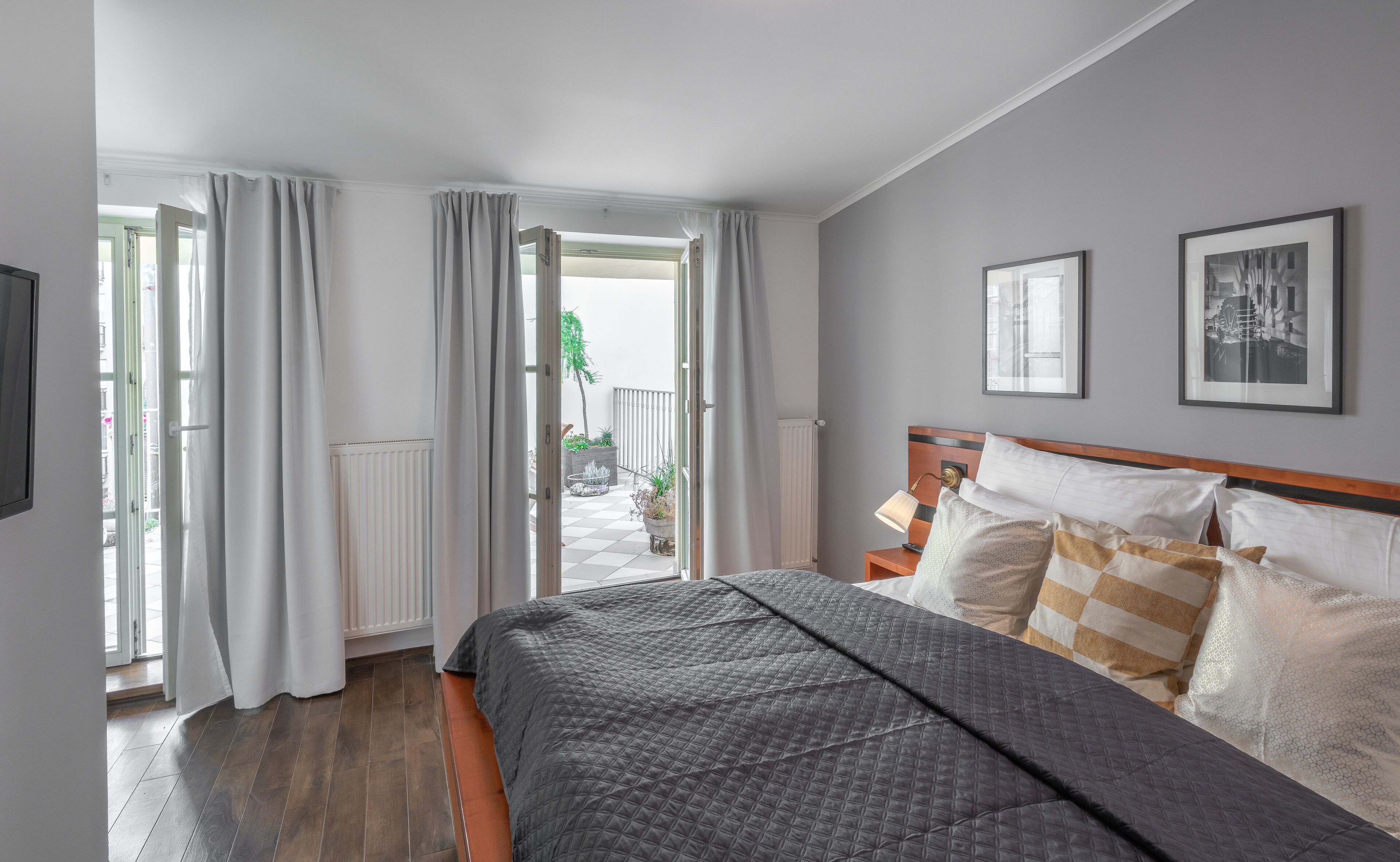 Een hotelkamer met een bed, nachtkastje, lamp en uitzicht op het balkon.
