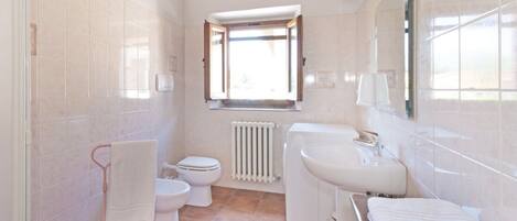 Ein Badezimmer mit Toilette, Bidet, Waschbecken und einem Fenster mit Aussicht.