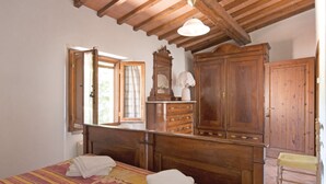 A bedroom with a wooden bed, a dresser, a mirror, and a window with curtains. - Podere Grossi (Borgo San Lorenzo)