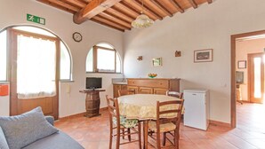 A cozy room with a wooden ceiling, a dining table with chairs, a sofa, a small refrigerator, and a television. - Podere Grossi (Borgo San Lorenzo)