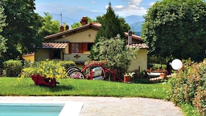 Une maison traditionnelle avec un jardin, une piscine et un tracteur rouge.