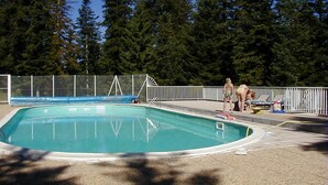 Una piscina con un borde cercado, rodeada de árboles altos.