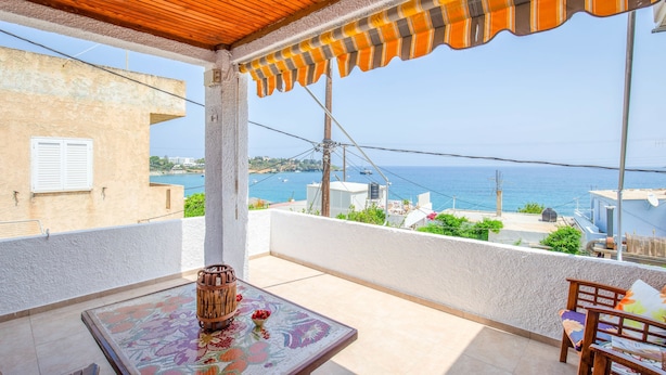 Ein Balkon mit Meerblick, einer Holzbalkendecke und einem Tisch mit einer Vase.