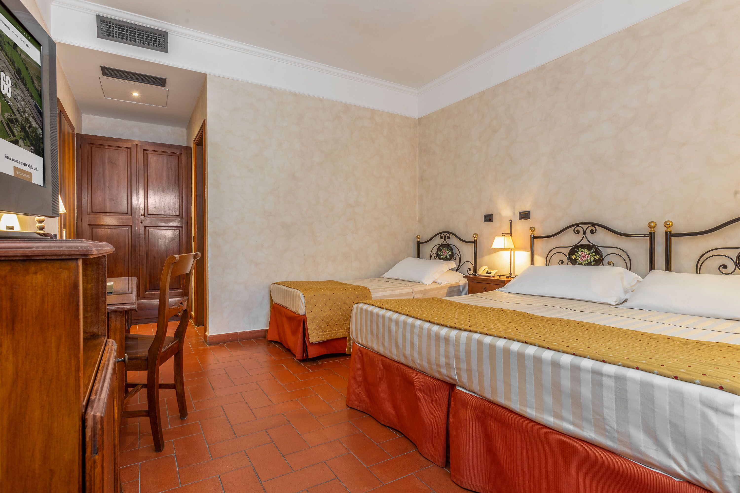 A hotel room with two single beds, a wooden desk, and a chair.