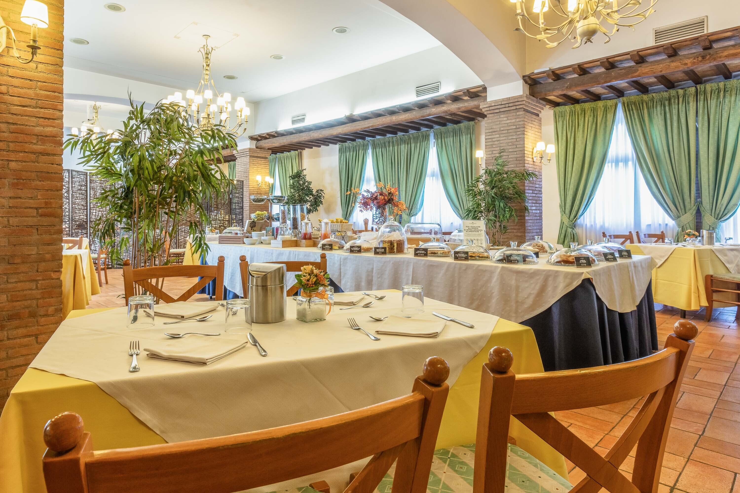 Un espace repas avec des tables rondes dressées pour les repas, entouré de murs en briques et de rideaux verts.
