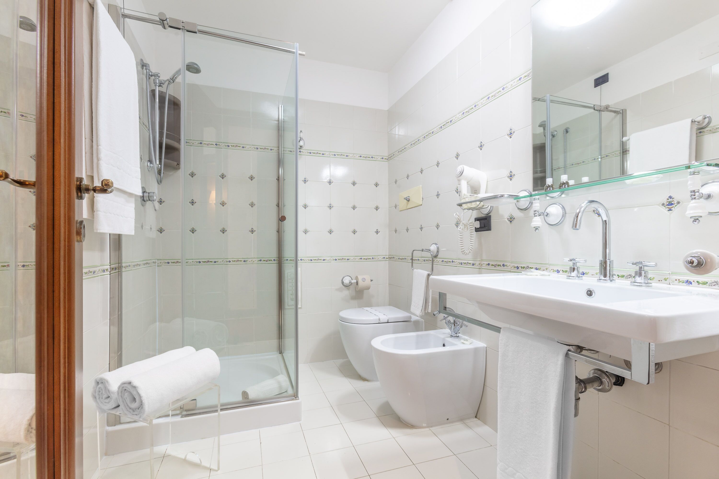 A modern bathroom with a glass-enclosed shower, a white sink, and a toilet.