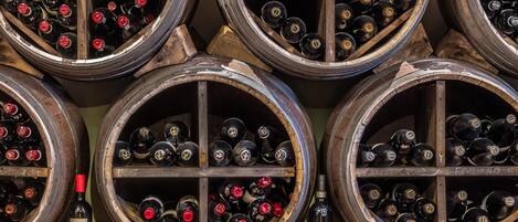 Une cave à vin où de nombreuses barriques en bois sont disposées en rangées, chacune contenant des bouteilles de vin.