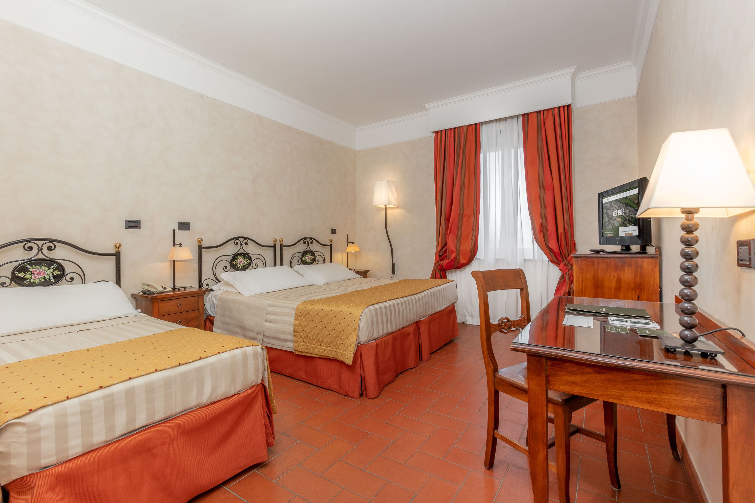 A hotel room with two beds, a desk, and a chair.