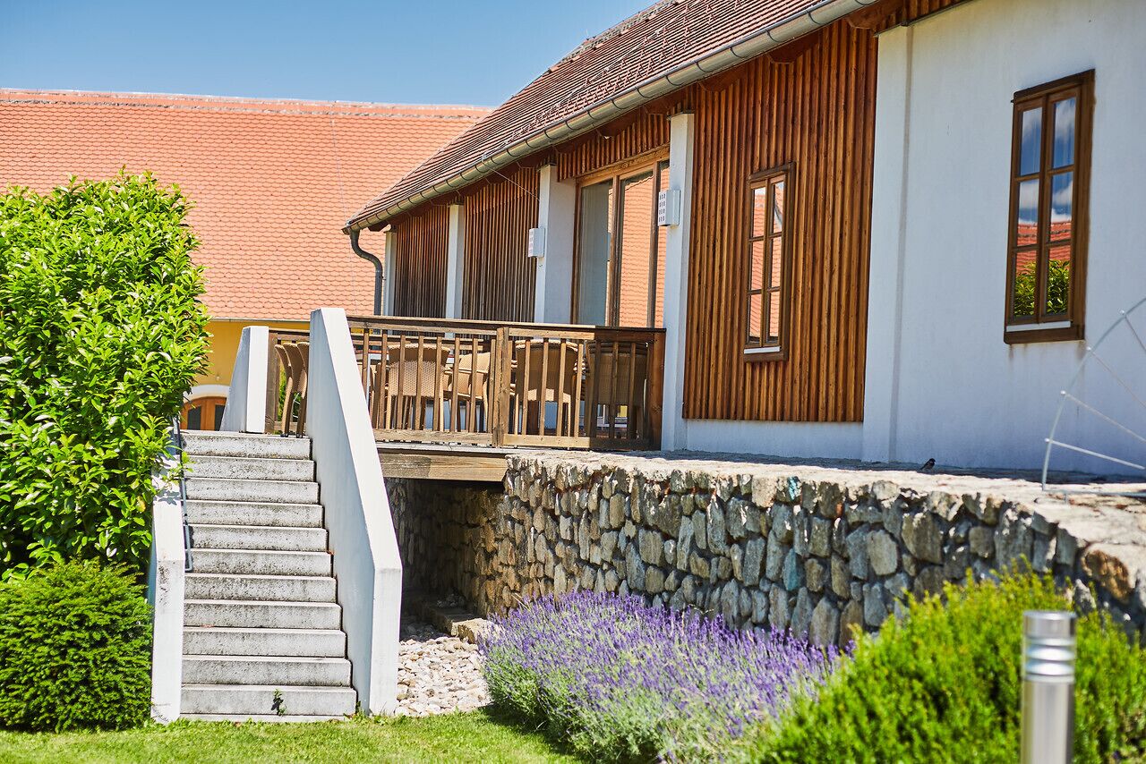 A building with a stone foundation, wooden exterior, and a balcony with a metal railing.