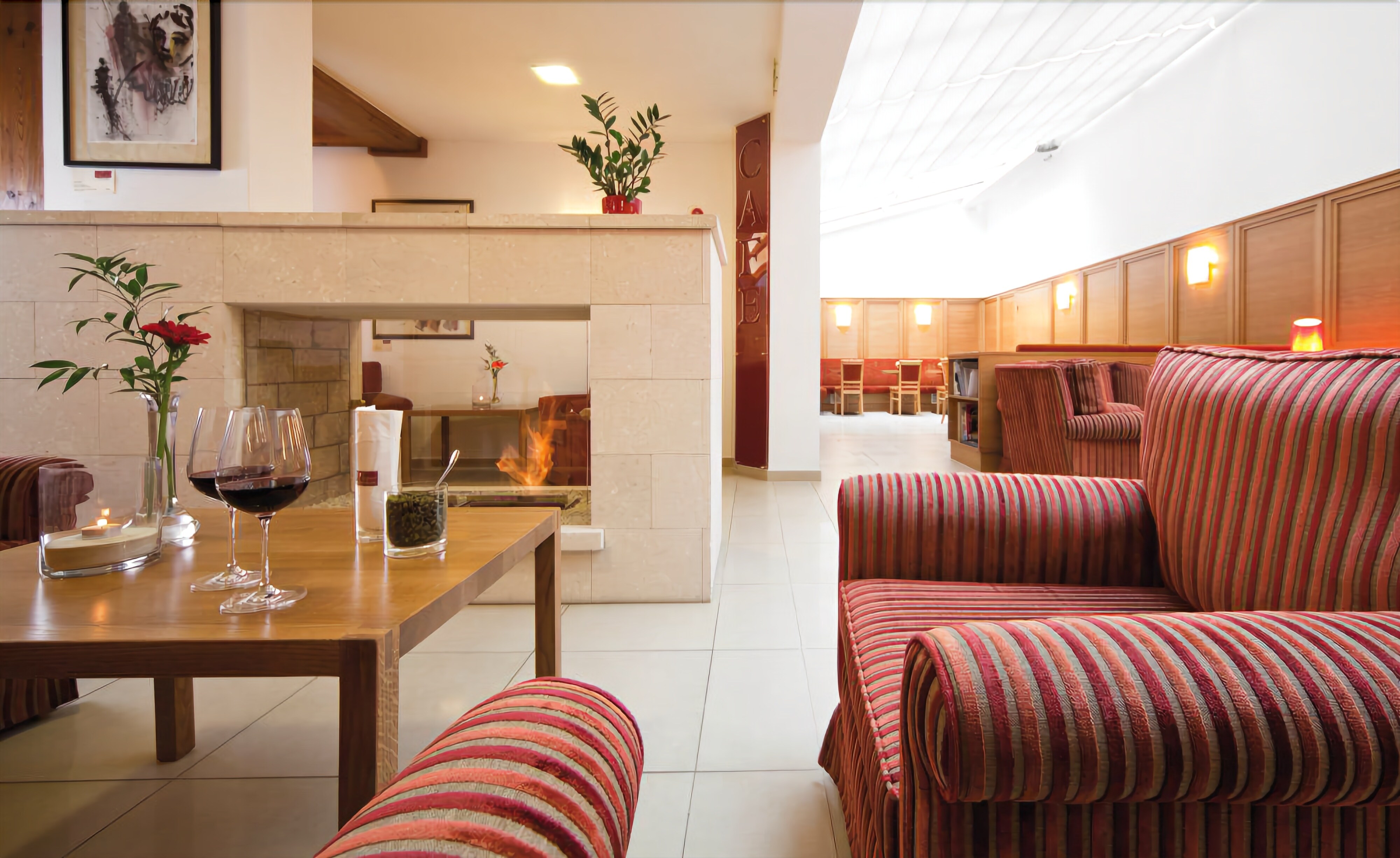Una sala moderna con una mesa de comedor de madera, sofás a rayas y una chimenea.