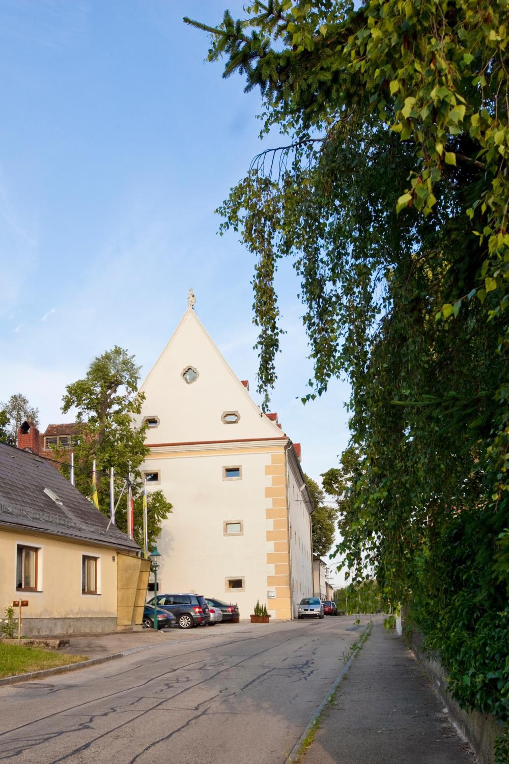 Une rue bordée d’un immeuble dont le toit a la forme d’un triangle et qui est surmonté d’une horloge.