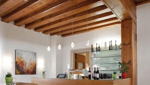Zona de bar moderna amb bigues de fusta, mostrador de vidre i tamborets.
