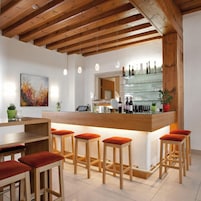 A modern bar area with wooden beams, a glass counter, and bar stools.