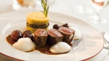 Une assiette de nourriture comprenant un dessert jaune, des boulettes blanches et des tranches de viande, le tout accompagné d’une branche de romarin.