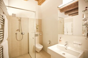 A modern bathroom with a glass-enclosed shower, a toilet, and a sink with a mirror above.