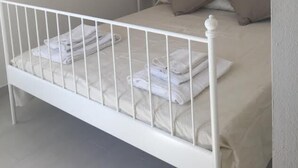 Un dormitorio con cama blanca, mesita de noche, lámpara y cabecero decorativo.