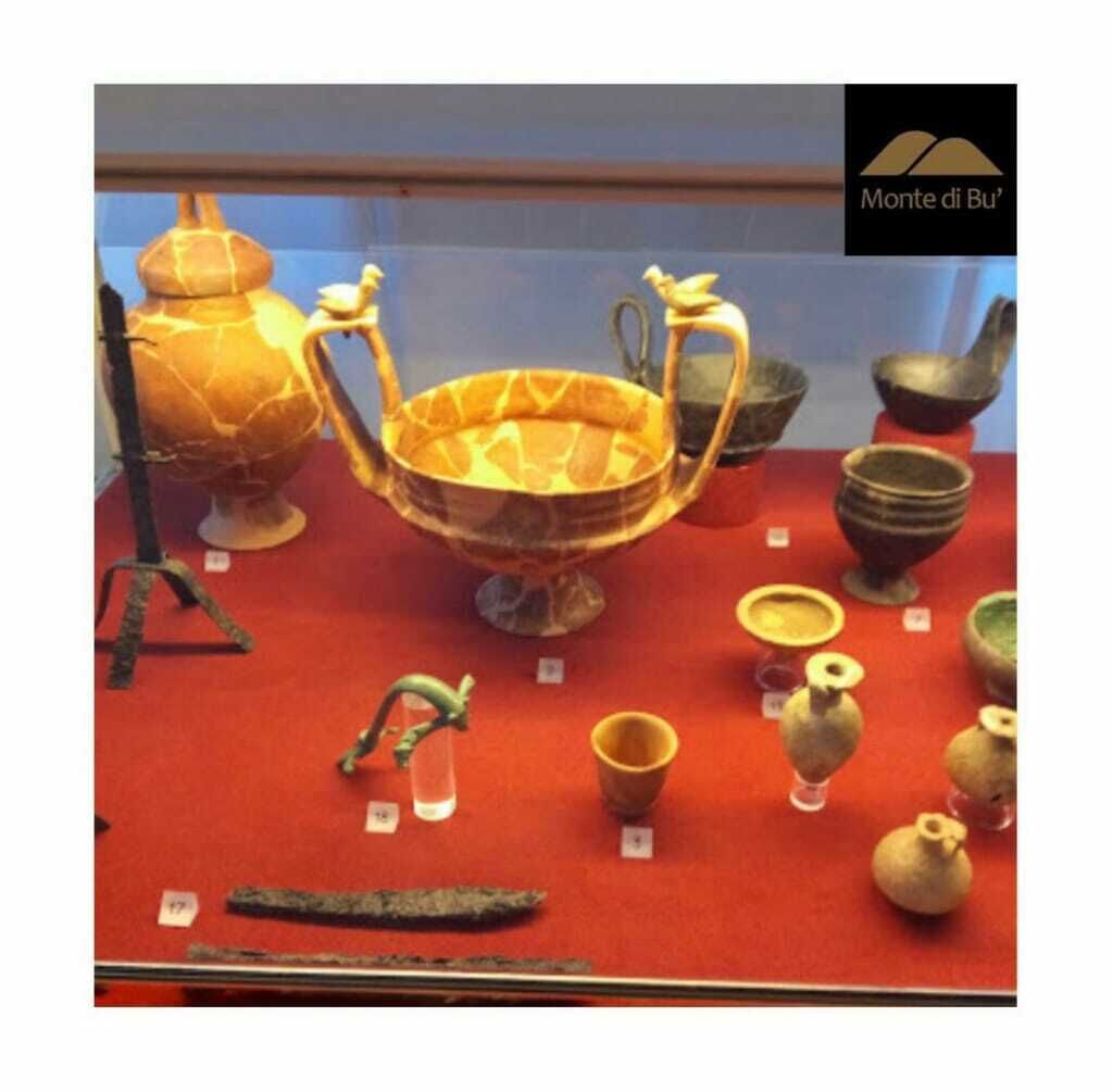 A display of ancient artifacts including a large golden bowl, smaller bowls, and a green-handled tool.