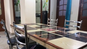 A dining table with a checkered tablecloth, surrounded by four chairs with metal frames and black cushions. - Utsav Bed & Breakfast (Noida)