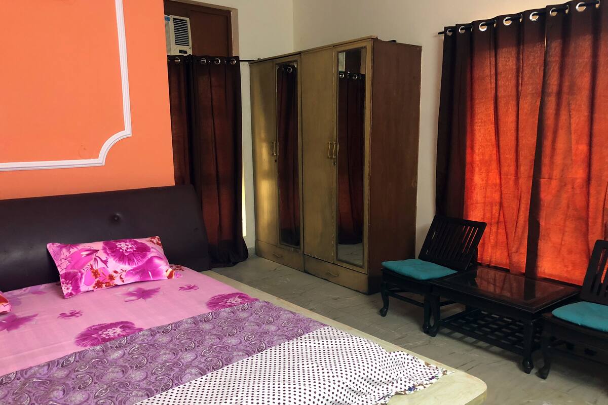 A bedroom with a bed, a wardrobe, a chair, and a table.