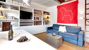 A modern living room with a blue sofa, a large red wall decoration, and a bookshelf filled with books. - Bragora Smoochy Attic Venice (Venice)