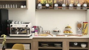 A modern kitchen with a coffee machine, various food items, and a dining area with a table and chairs. - El Malecon (Sarria)