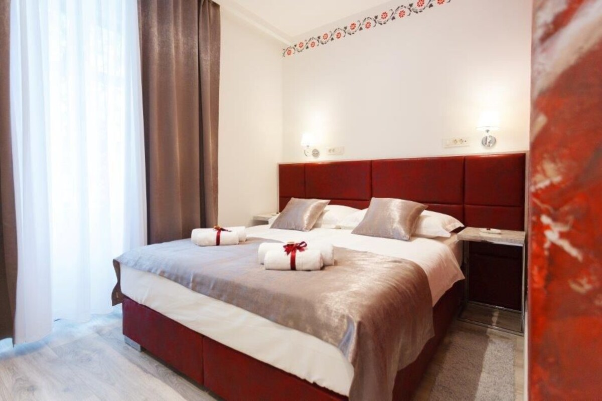 A hotel room with a large bed, bedside tables, and a decorative wall pattern.