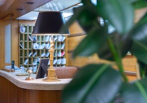 En receptionsdisk med en lampa, en inramad tavla och en bokhylla full med böcker.