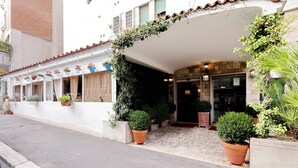 Un bâtiment à la façade blanche, avec un porche carrelé et des plantes en pot.