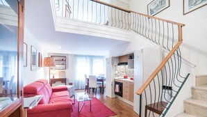 Un salon moderne avec un canapé rouge, une table à manger et un escalier doté d’une rampe en bois.
