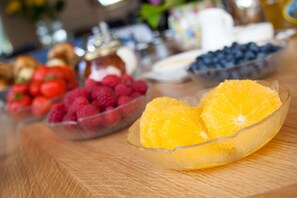 A table with bowls of various fruits including strawberries, raspberries, blueberries, and oranges. - Sunny Brae (Nairn)