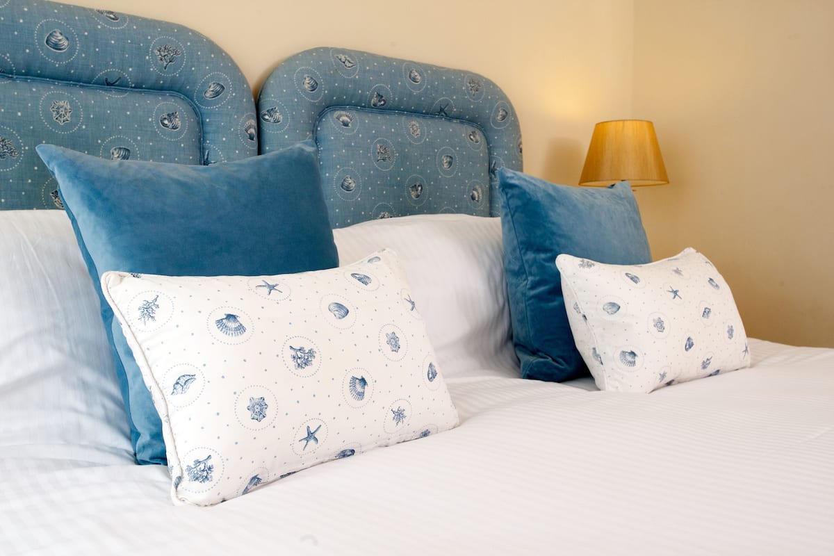 A bed with a headboard, pillows, and a lamp.