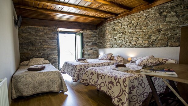A room with two beds, a wooden ceiling, stone walls, and a wooden floor. - Pension Siete en el Camino (Sarria)