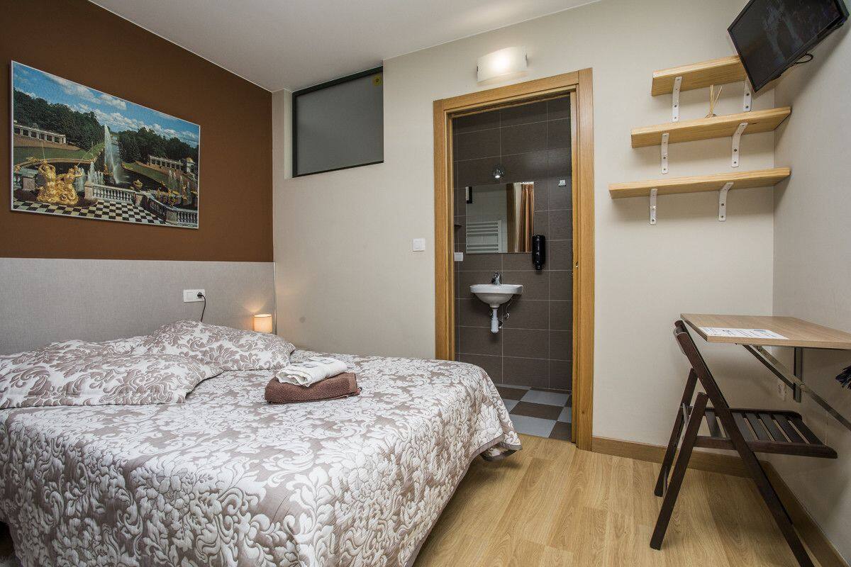 Een hotelkamer met een bed, een bureau, een wastafel en een schilderij aan de muur.