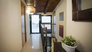 A hallway with a wooden ceiling, a staircase, and a potted plant. - Pension Siete en el Camino (Sarria)