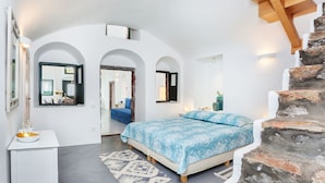 A bedroom with a bed, a white dresser, a mirror, and a staircase. - Casa d'Argento (Santorini)