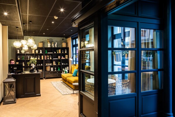 A modern living room with a sofa, a coffee table, and a bookshelf. - Hôtel Lanjuinais (Rennes)