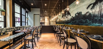 Un restaurant doté d’un long comptoir, de banquettes et d’une fresque représentant une scène de forêt.