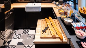 Una cocina moderna con una isla central, un fregadero y una barra desayunadora con diversos alimentos y utensilios.