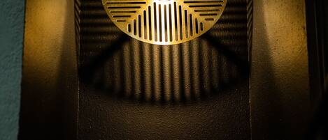 A ventilation grille with a circular pattern and a central hole, mounted on a dark surface.