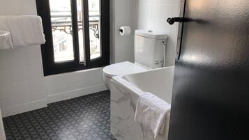 A bathroom with a toilet, a bathtub, and a window.