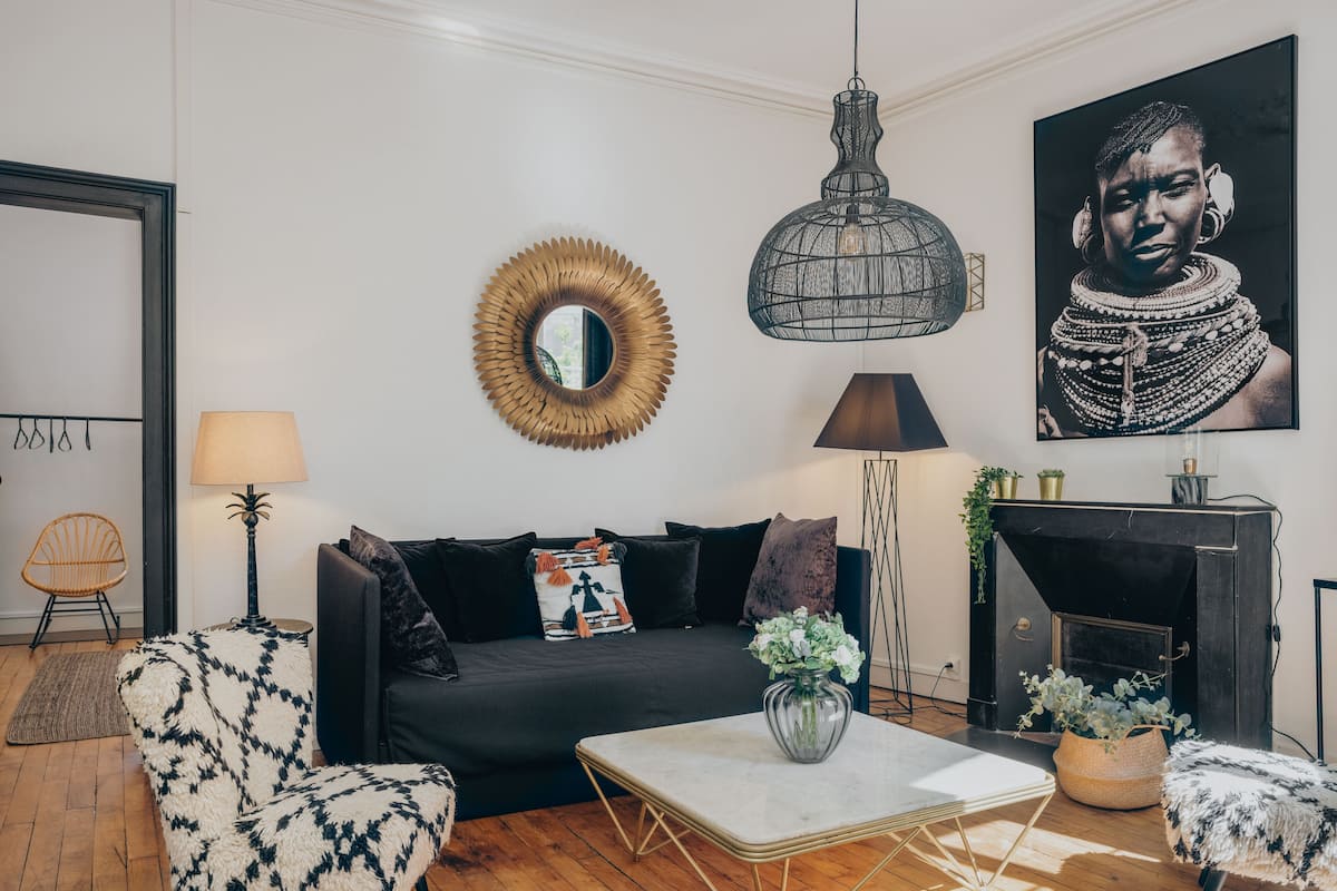 A modern living room with a dark sofa, patterned armchairs, a white coffee table, and a hanging pendant light.