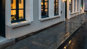 Fachada de hotel con un letrero que dice "HOTEL LANJUINAIS", con una hilera de ventanas con luces interiores iluminadas, una fachada limpia y una calle estrecha al frente.
