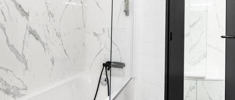 A modern bathroom with a marble wall, a black door, and a patterned floor.