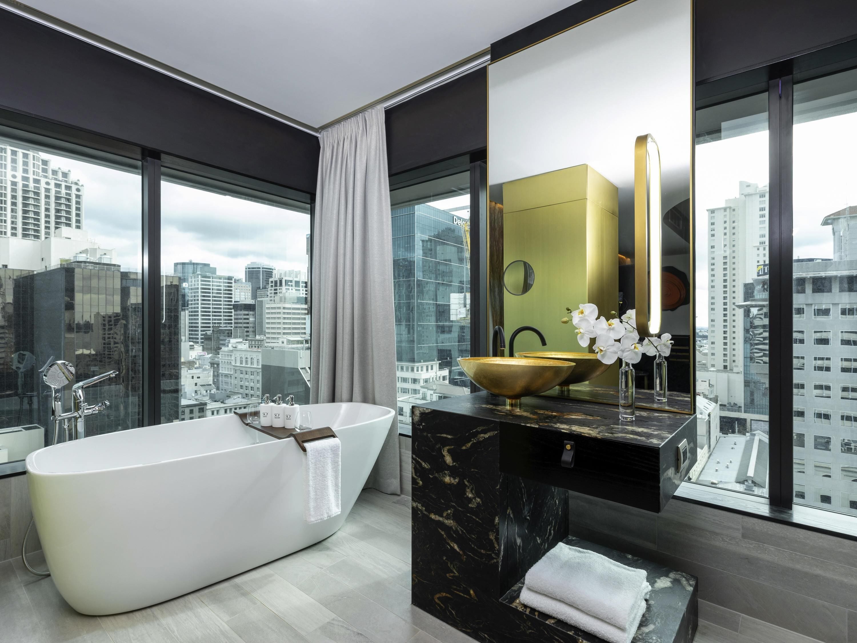 A modern bathroom with a freestanding bathtub, a gold bowl sink, and a large mirror.