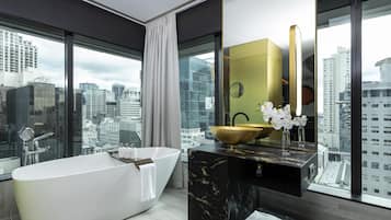 A modern bathroom with a freestanding bathtub, a gold bowl sink, and a large mirror.